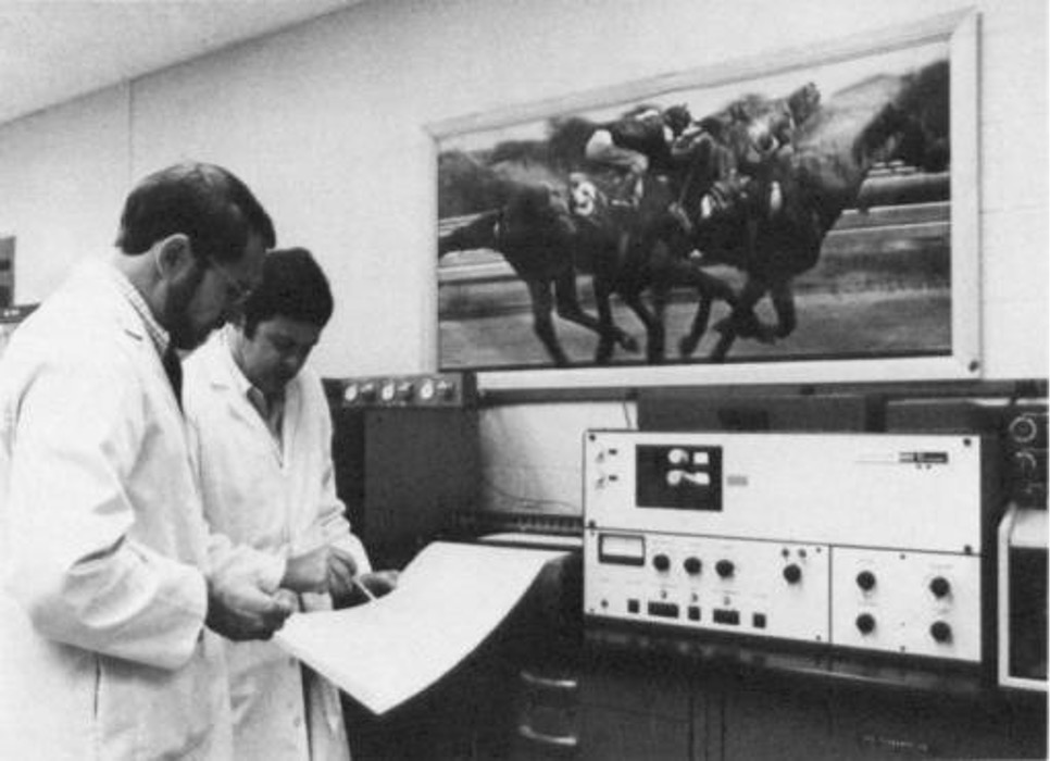 Two scientists looking at data in front of a machine in 1978